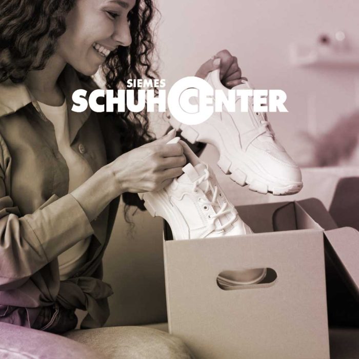 Kundin öffnet ihr Bestellpaket von SIEMENS SCHUHCENTER und betrachtet freudig ihre neuen Sneaker.
